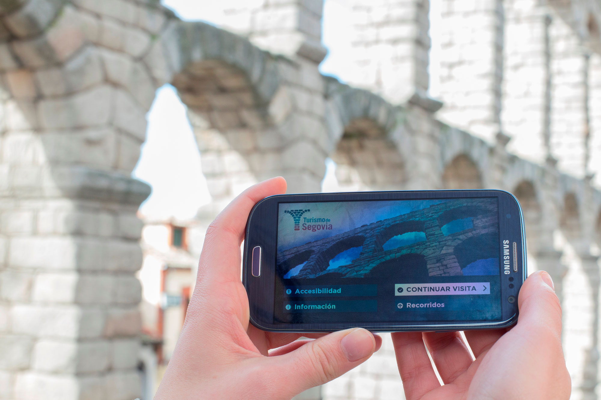Turista usa la app Segovia junto al acueducto